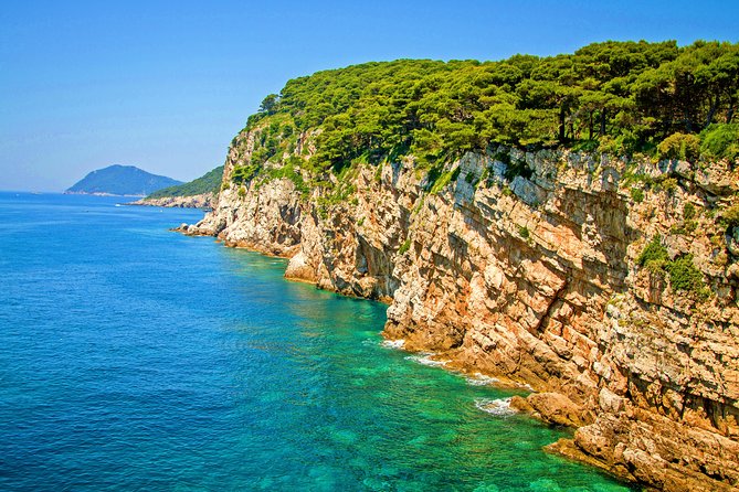 Limestone cliffs dropping into clear Adriatic water on the Blue Cave run